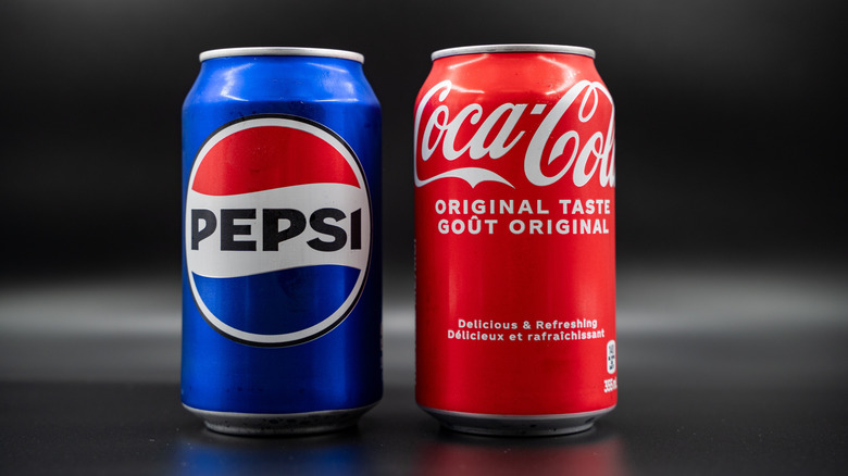 Pepsi and Coca Cola cans against black background