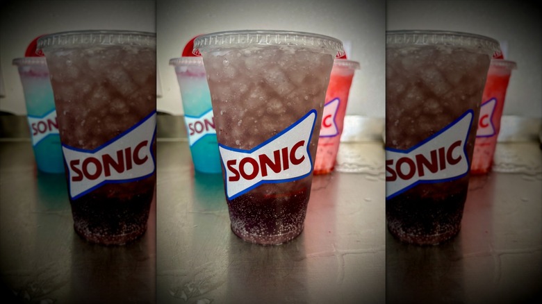Purple O drink in clear Sonic cup with other Sonic drinks behind it