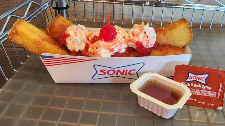 Strawberry shortcake French toast with a cherry on top and syrup on the side