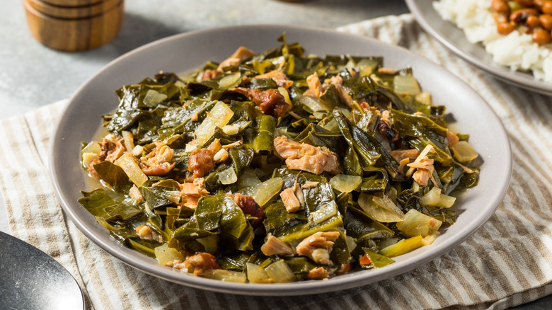 A white bowl filled with collard greens and pieces of pork