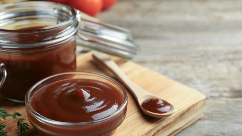 A heavy tomato barbecue sauce in a small bowl next to a spoon