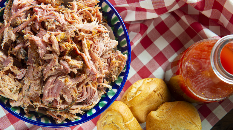 A bowl of barbecue with a bottle of light tomato barbecue sauce