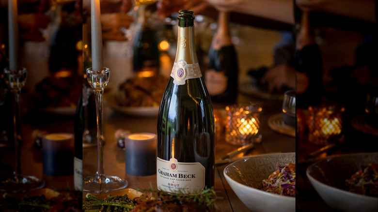 bottle of sparkling wine with candlelit dinner table atmosphere