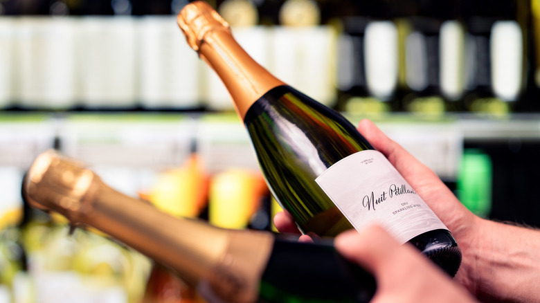 hands with two bottles of sparkling wine