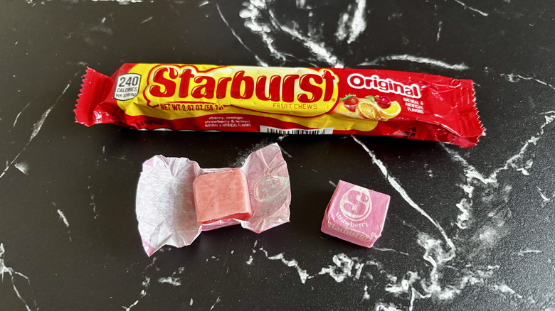 Starburst candy package next to wrapped and unwrapped strawberry Starburst