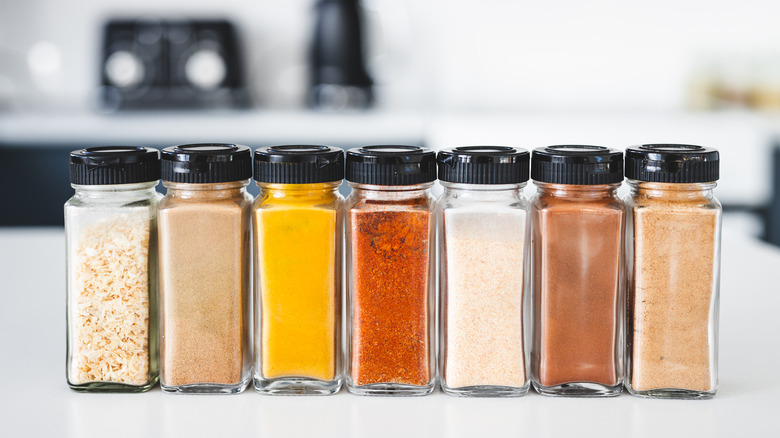 Several glass jars filled with spices stacked in a row