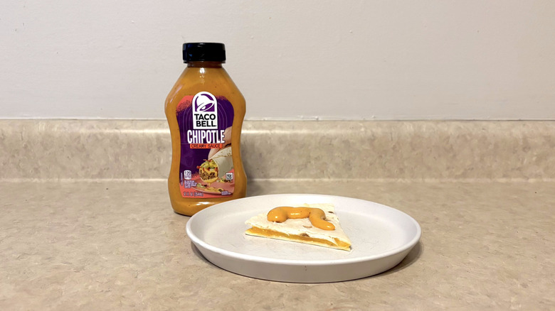 Taco Bell creamy chipotle sauce on quesadilla on white plate on countertop