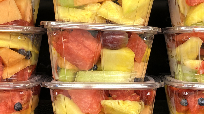Pre-cut fruit in plastic tubs, stacked on grocery store shelf