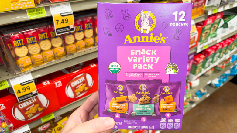 Hand holding box of Annie's snack variety packs in grocery store