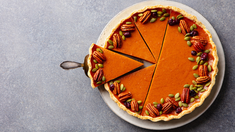 Cleanly sliced pumpkin pie placed against a gray background