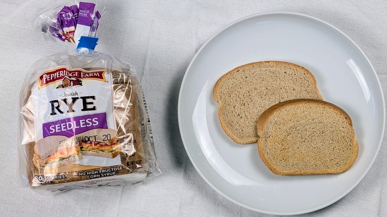 A loaf of Pepperidge Farm seedless rye bread next to a white plate with two slices of bread on a white tablecloth