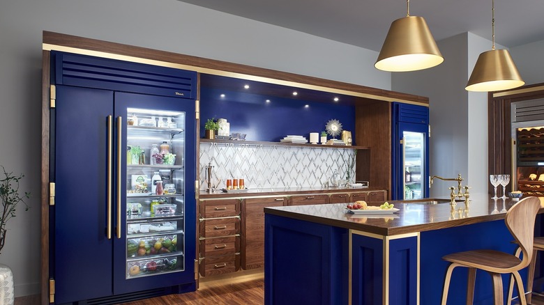 Stunning navy blue kitchen with gold accents and dark wood throughout