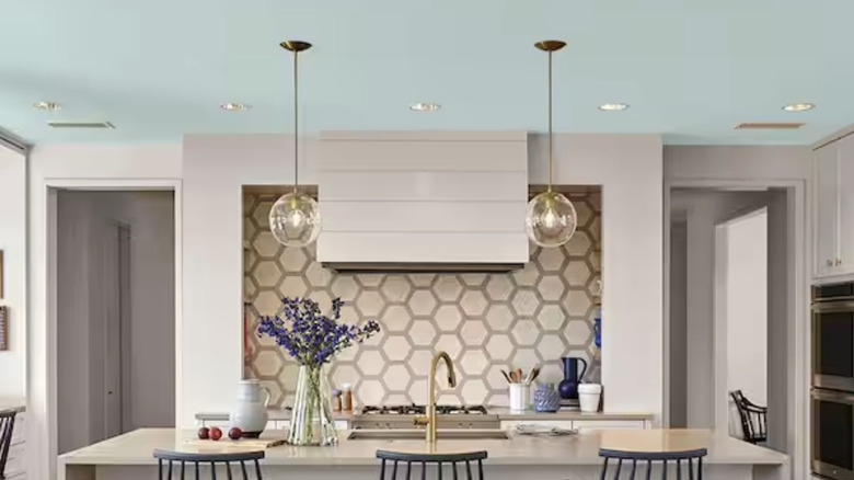 A mostly white kitchen with very light blue ceilings