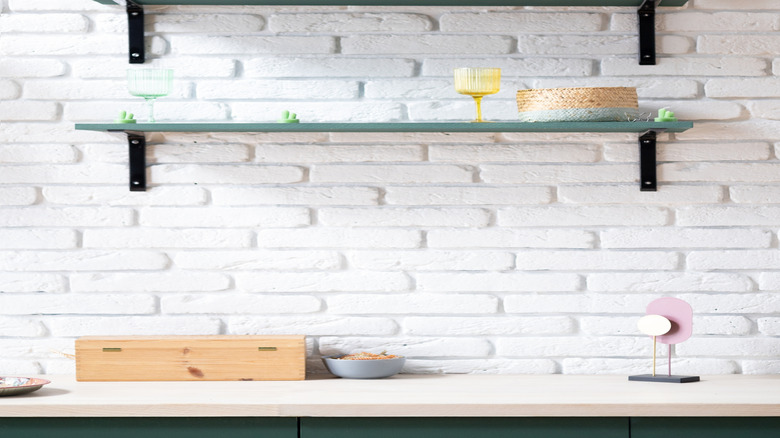 Green shelves with minimal decor attached to white brick wall