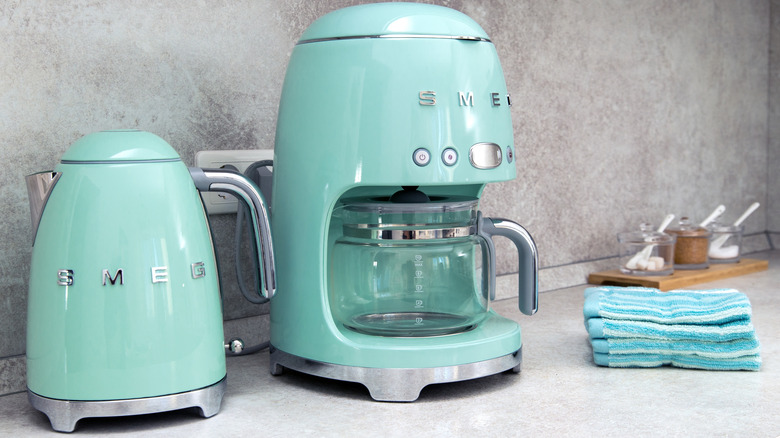 Brightly colored coffee maker and kettle placed against gray backdrop