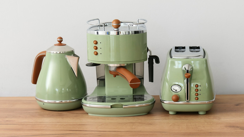 Coffee machine, toaster and electric kettle on wooden table in kitchen