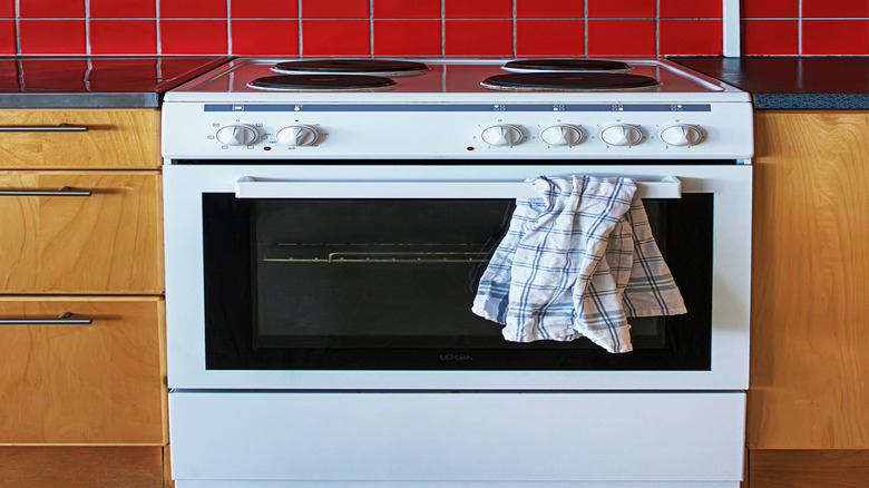 White stove and oven in kitchen with red tile backsplash and wooden cabinets