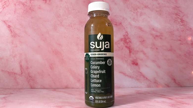 Bottle of Suja Uber Greens organic juice on pink background