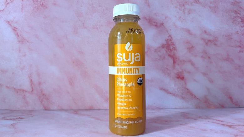 Bottle of Suja Citrus Pineapple organic juice on pink background