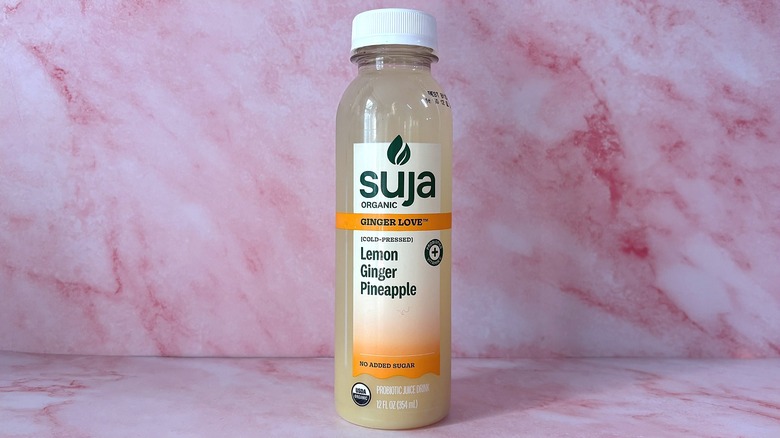 Bottle of Suja Ginger Love organic juice on pink background