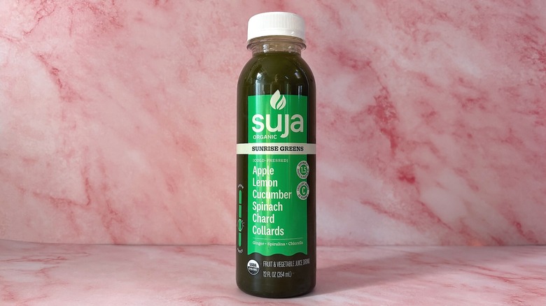 Bottle of Suja Sunrise Greens organic juice on pink background