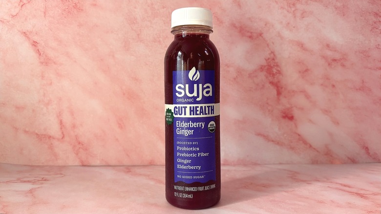 Bottle of Suja Elderberry Ginger organic juice on pink background