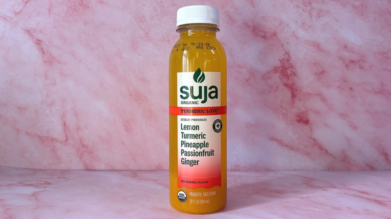 Bottle of Suja Turmeric Love organic juice on pink background