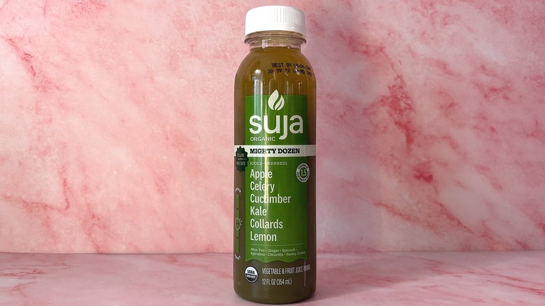 Bottle of Suja Mighty Dozen organic juice on pink background