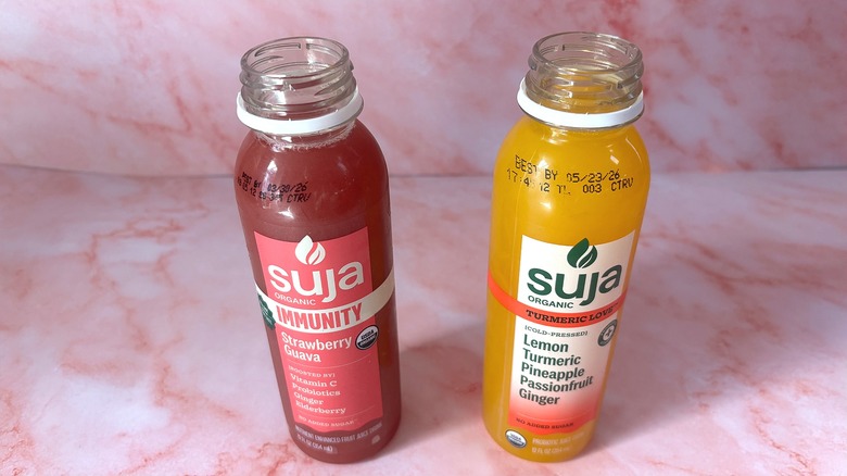 Angled down shot of two Suja organic juices on pink surface