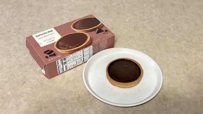 Favorite Day chocolate tart on white plate with box on neutral background