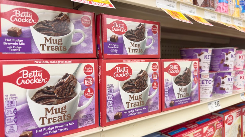 display of Betty Crocker mug cake mixes on a supermarket shelf, regular cake mixes visible on the shelf below