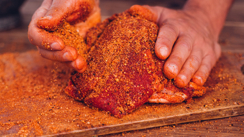 Person coating meat in a rub