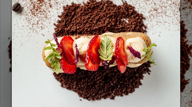 Decorative eclair on bed of coffee grounds crumble