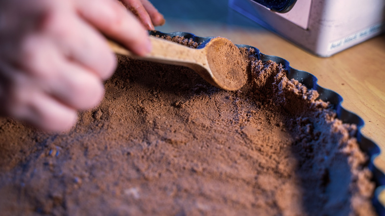 Close-up of hand pressing chocolate crust into tart pan