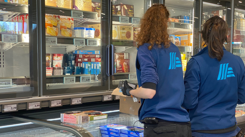 Two employees are performing an inventory check in the frozen food aisle at Aldi