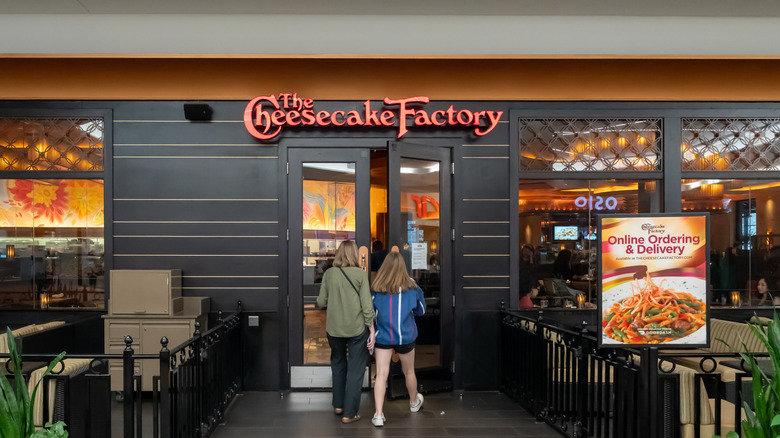 Two people walking into The Cheesecake Factory