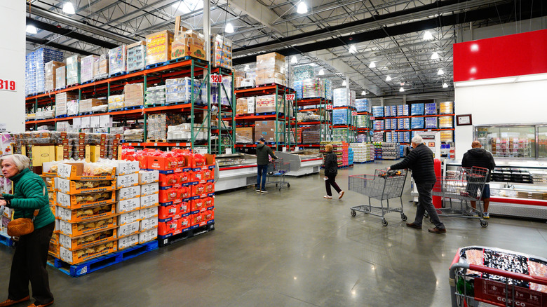Interior of Costco with stocked aisles and shoppers with carts