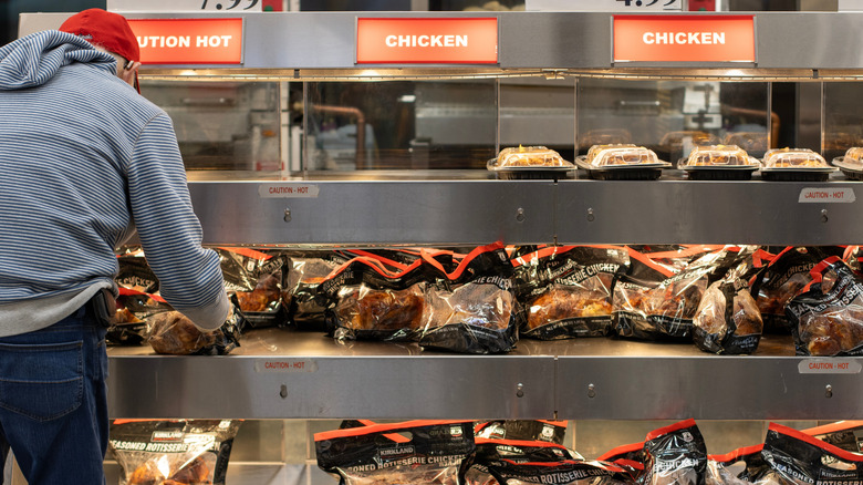 A customer grabs a rotisserie chicken from the shelf at a Costco store