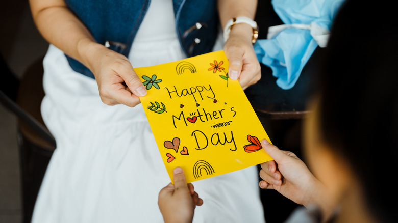 Close-up of woman receiving greeting card for Mother's day