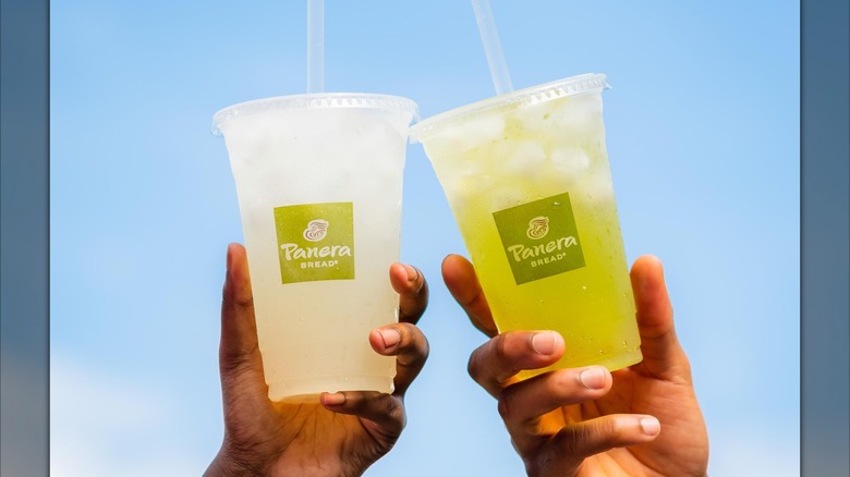 Two hands holding iced drinks from Panera in front of blue sky