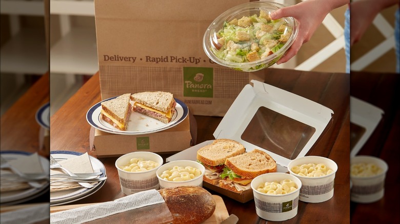 Assortment of sandwiches, mac and cheese, salads, and breads with takeout containers