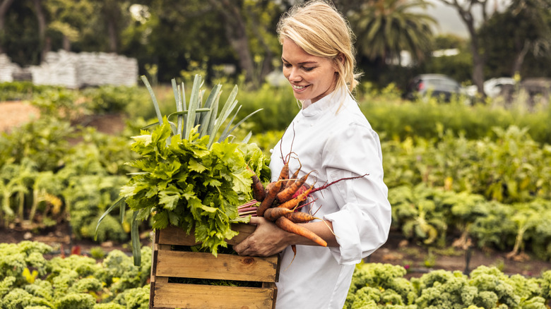 Female chef with a crate of fresh vegetables.