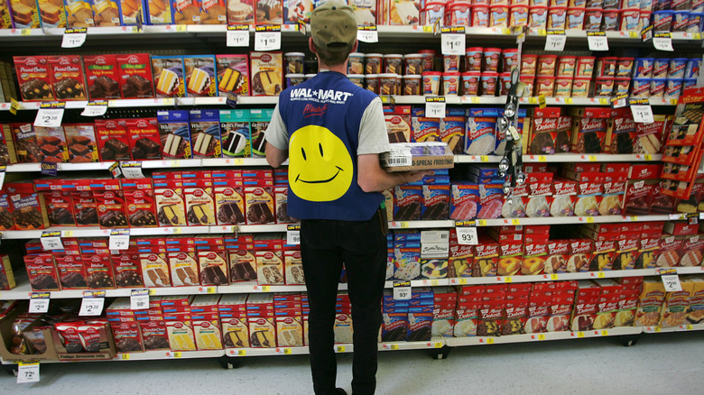 Walmart employee restocking items in the boxed cake aisle of Walmart