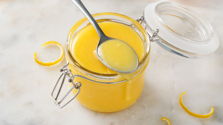 Jar of lemon curd with spoon resting on top