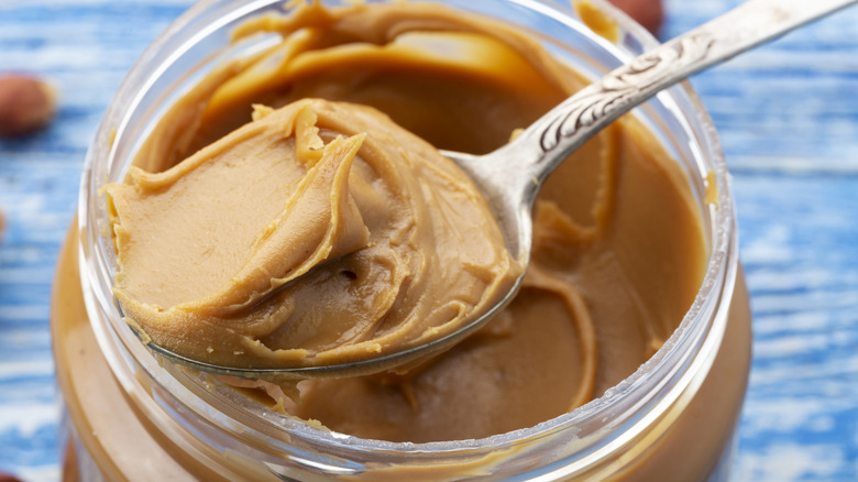 Spooning creamy peanut butter from opened jar