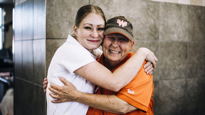 Whataburger employees hug each other and smile.