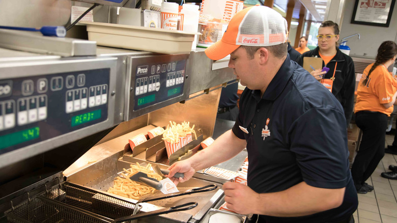 Whataburger employee cooks fries in restaurant.