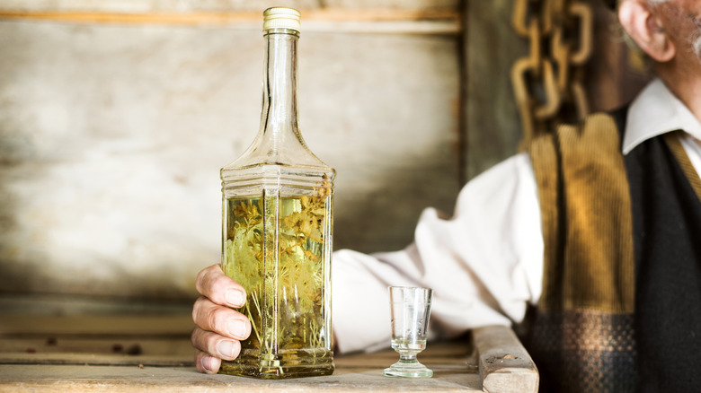 Close-up of of bottle of herbal spirit held by an old man.