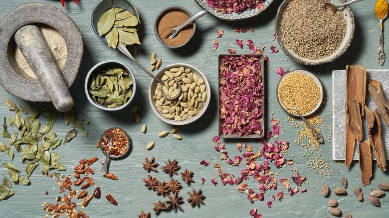 A variety of spices on a rustic blue table.
