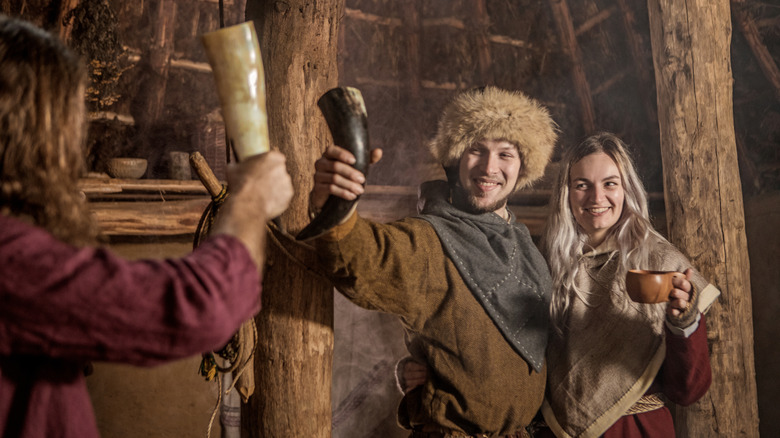 A family group of viking villagers having a fun meeting in a warm settlement hall.